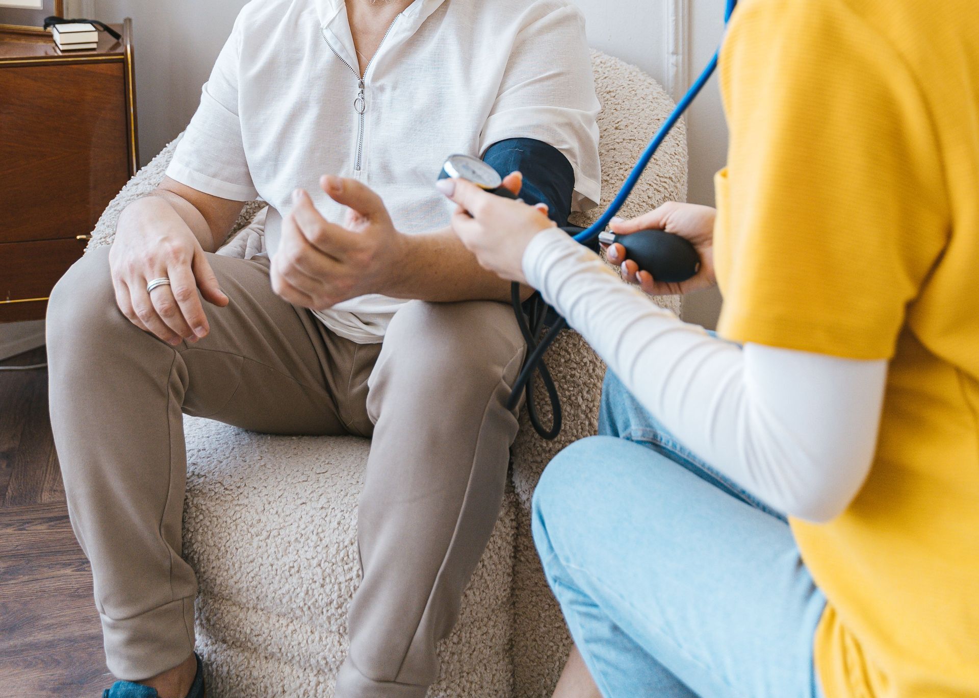 A healthcare professional checks an elderly man's blood pressure in a cozy room.